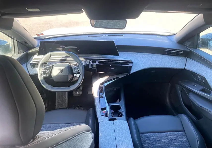 Vue intérieure avant du Peugeot 5008 Hybrid 145 allure e-dcs6 2025, avec tableau de bord gris clair et volant cuir noir.