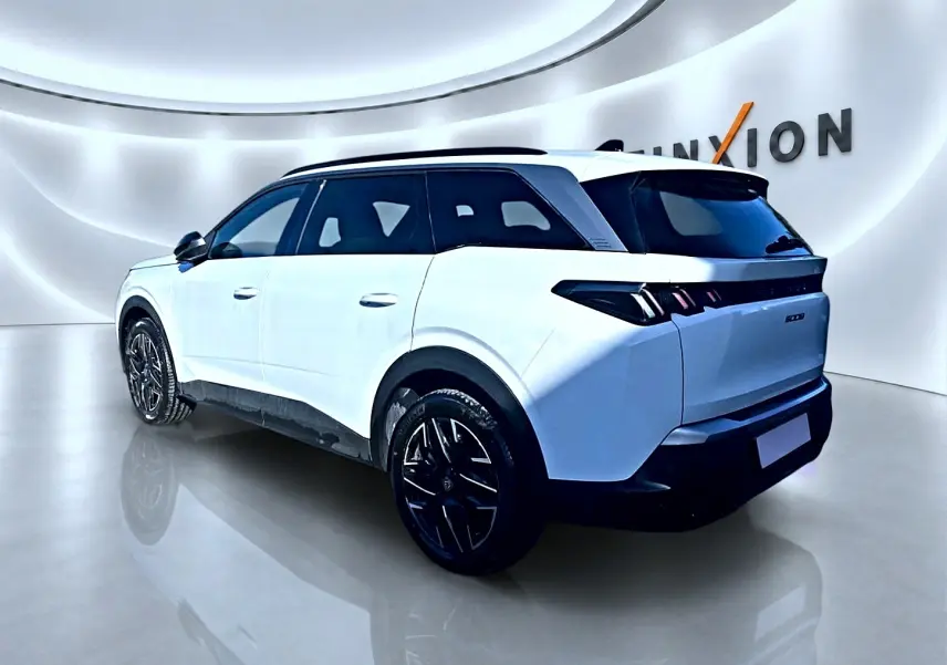 Peugeot 5008 Hybrid blanc en 3/4 arrière droit, avec jantes noires et vitres arrière surteintées dans un showroom.