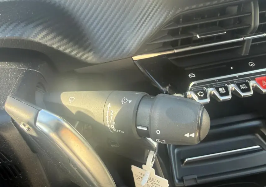 Gros plan sur la commande d’essuie-glace côté gauche du tableau de bord du Peugeot 208 Hybrid blanc 2024.