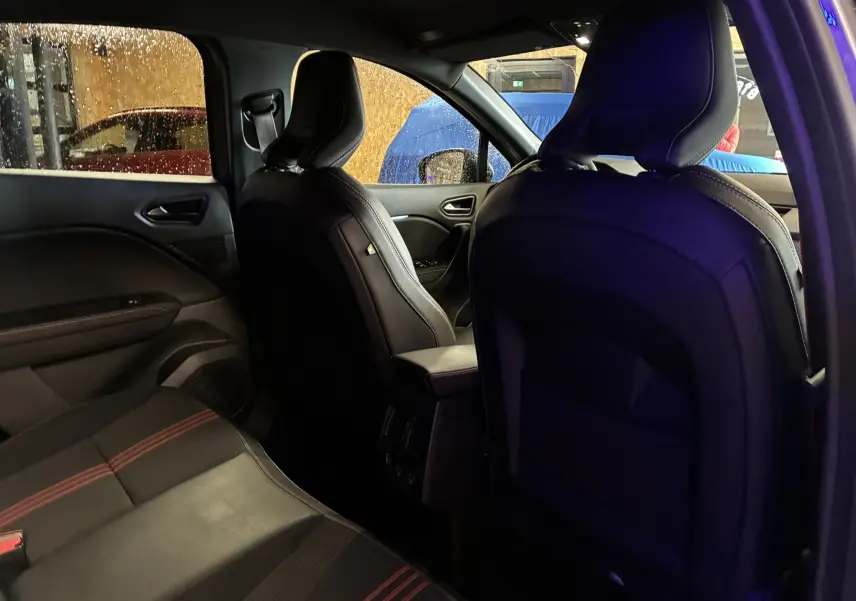 Vue intérieure arrière du Renault Captur gris 2021, montrant les sièges avant en tissu noir avec surpiqûres rouges.