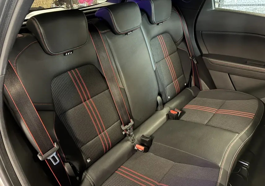 Vue intérieure de la banquette arrière du Renault Captur gris, avec sièges noirs et surpiqûres rouges contrastantes.