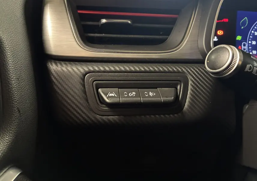 Gros plan sur les commandes de réglage d'assistance et d'éclairage du tableau de bord du Renault Captur gris 2021.
