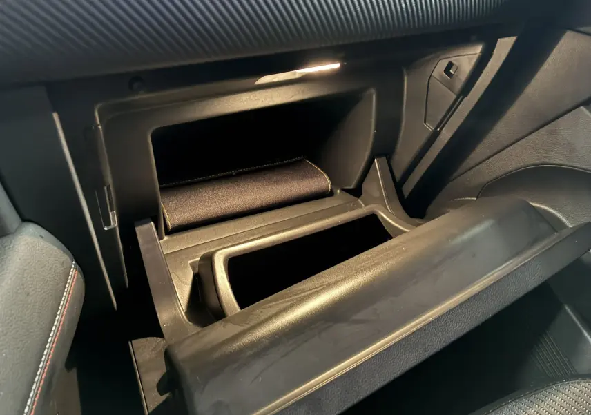 Gros plan de la boîte à gants ouverte côté passager dans l’habitacle noir du Renault Captur gris 2021.