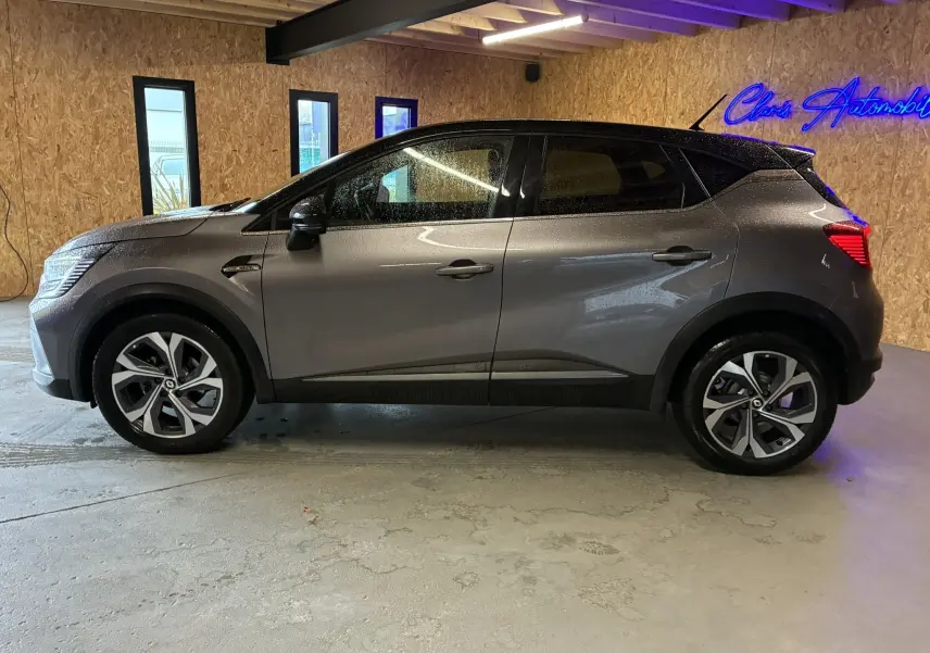 Vue de profil côté gauche d'un Renault Captur gris 1.3 TCE 140 EDC RS Line avec jantes alliage et toit noir.