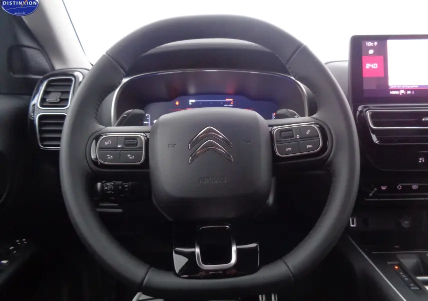 Vue rapprochée du volant noir du Citroën C5 Aircross 2022 avec commandes intégrées et tableau de bord digital.