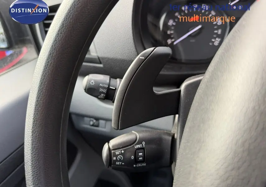 Gros plan sur les commandes au volant du fourgon Opel Vivaro gris, montrant le régulateur de vitesse et palettes de boîte automatique.