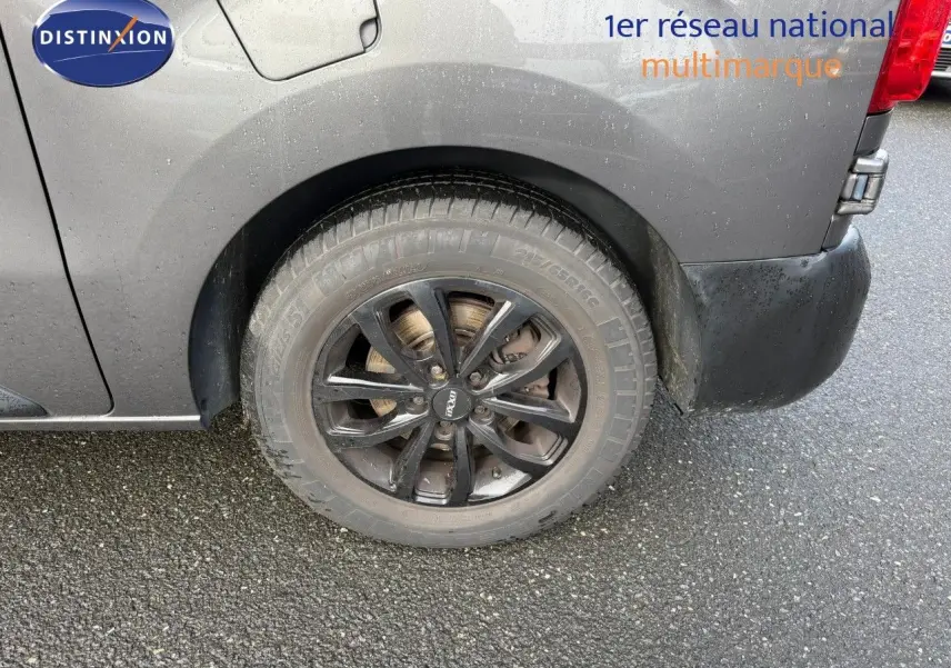 Gros plan sur la roue arrière droite noire du fourgon Opel Vivaro gris Pierre de Lune métallisé.