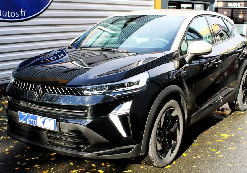 Renault Captur 2025 noir métal et toit gris en 3/4 avant droit, avec calandre lumineuse et jantes noires biton.