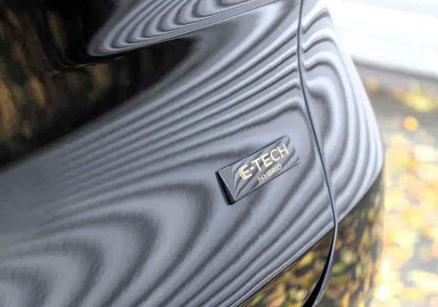 Renault Captur 2025 noir métal avec toit gris, vue 3/4 avant droit, stationné devant un bâtiment commercial.