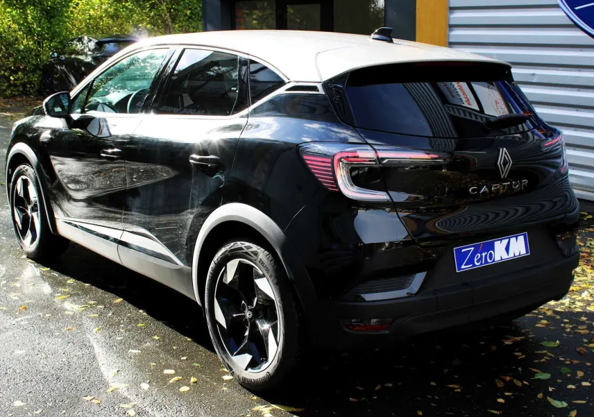 Vue 3/4 arrière droite du Renault Captur 2025 noir métal avec toit gris et jantes biton distinctives.