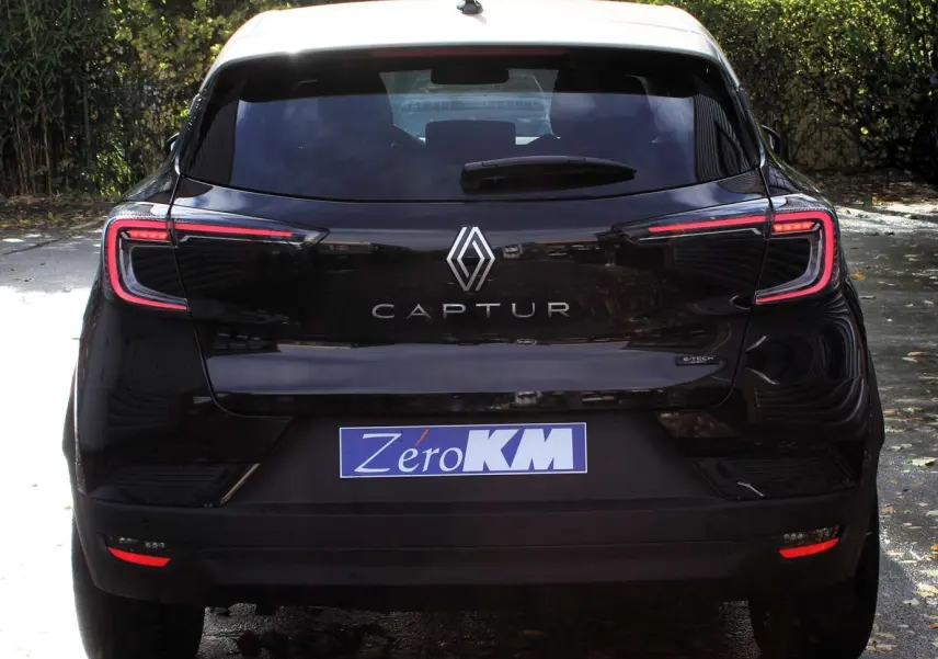 Vue 3/4 arrière droite du Renault Captur noir métal avec toit gris, jantes biton et feux arrière LED distinctifs.