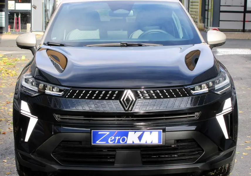 Vue frontale d'un Renault Captur 2025 noir métal avec toit gris, éclairage LED distinctif et plaque Zéro KM.