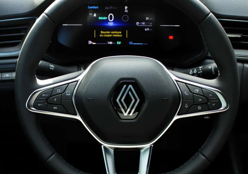 Volant noir du Renault Captur 2025 hybride avec commandes intégrées et tableau de bord numérique en arrière-plan.