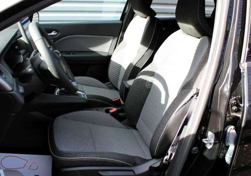 Intérieur du Renault Captur 2025, sièges bi-ton gris clair et foncé, vue côté conducteur porte ouverte.