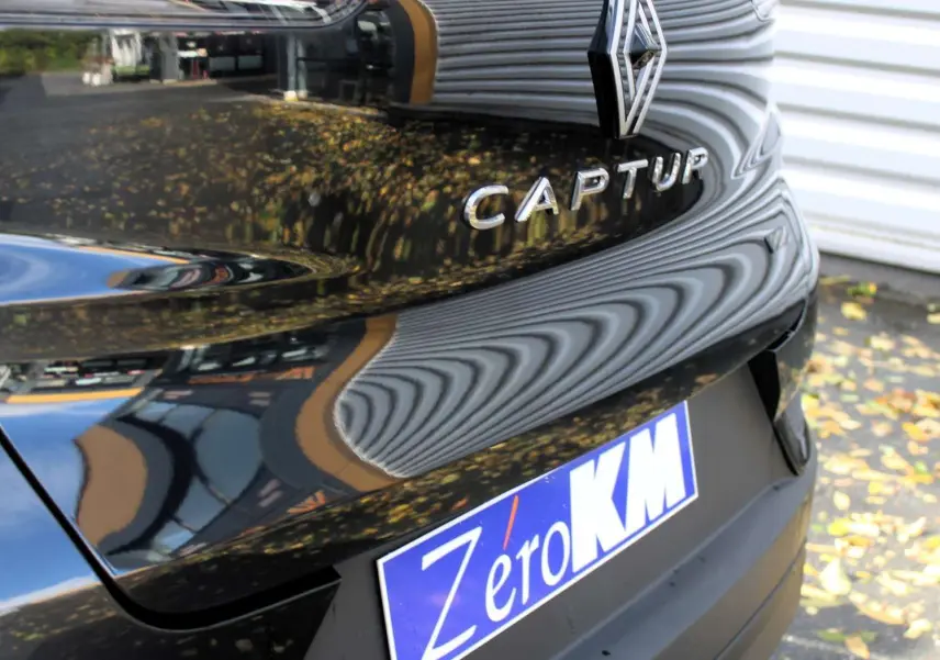 Gros plan sur l'écusson E-TECH Hybrid sur la carrosserie noire métal du Renault Captur 2025.