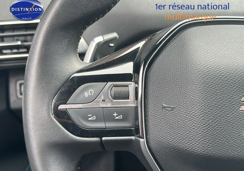 Gros plan sur le volant cuir noir du Peugeot 5008 bleu 2024 avec commandes audio intégrées côté gauche.