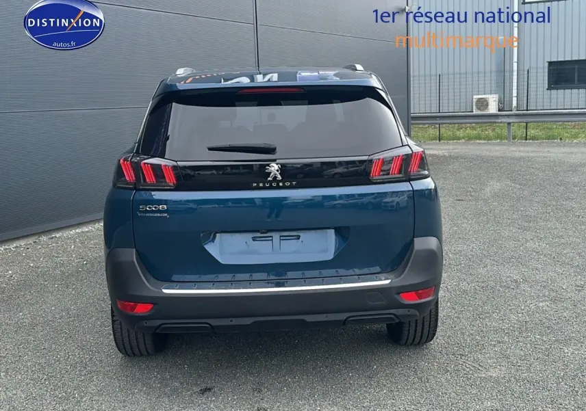 Vue arrière d'un Peugeot 5008 bleu 2024 avec feux LED à effet 3D et barres de toit en aluminium visibles.