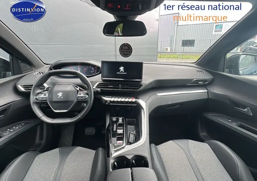 Habitacle avant du Peugeot 5008 2024 avec tableau de bord noir et écran tactile central affichant le logo Peugeot.