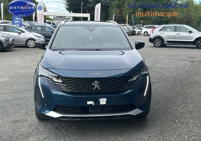 Vue frontale d'un Peugeot 5008 bleu 2024 avec calandre à damiers chromés et feux LED à effet 3D.