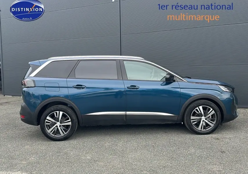 Profil droit d'un Peugeot 5008 bleu 2024 avec jantes alliage et vitres teintées sur fond gris.