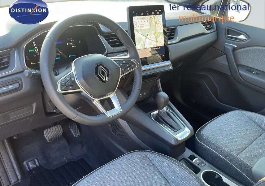 Intérieur avant du Renault Captur E-Tech hybride 2025, tableau de bord moderne avec écran tactile vertical et volant multifonction.