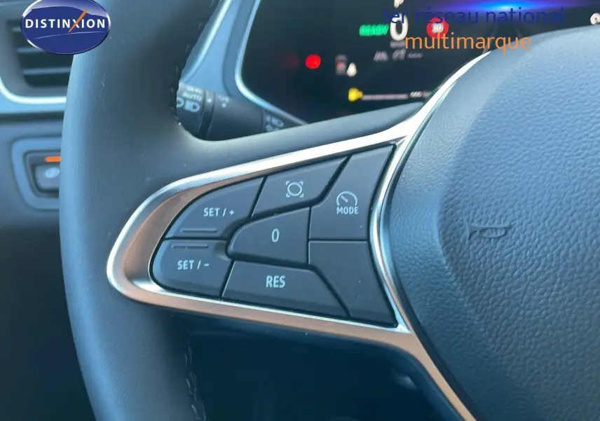 Gros plan sur les commandes au volant du Renault Captur E-Tech blanc nacré avec toit noir, version hybride 2025.