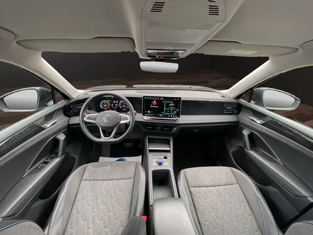 Vue intérieure avant du Volkswagen Tiguan noir 2024, tableau de bord numérique et écran tactile central lumineux.