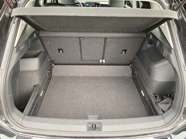 Coffre ouvert vu de l'arrière d'un Volkswagen Tiguan noir 2024, espace de chargement vide et tapis gris.