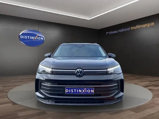 Vue frontale d’un Volkswagen Tiguan III noir 2024, avec calandre large et logo VW centré, en showroom.
