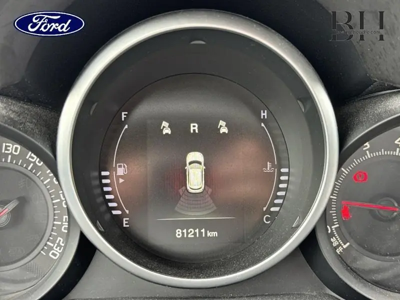 Vue rapprochée du tableau de bord numérique d'une Fiat 500X noir Cinéma pastel, affichant le compteur kilométrique et les capteurs de stationnement.