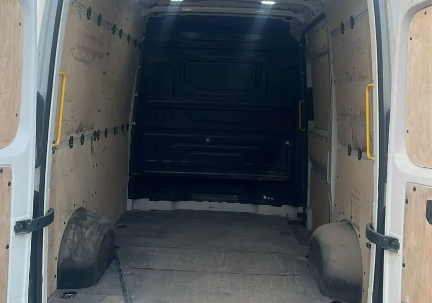 Vue arrière ouverte du Volkswagen Crafter blanc montrant l'intérieur vide et le plancher renforcé avec hayon et attelage.