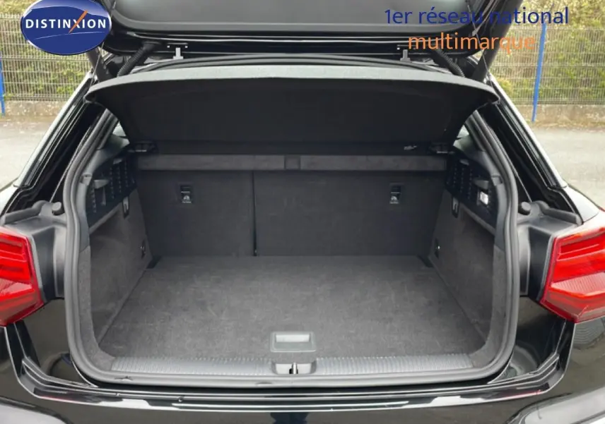 Coffre ouvert vu de l'arrière d'un Audi Q2 noir mito metal, montrant un espace de chargement propre et spacieux.