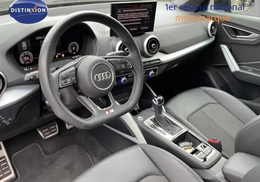 Vue intérieure côté conducteur de l'Audi Q2 35 2.0 TDI S-Line 2025, avec volant cuir perforé et tableau de bord digital.