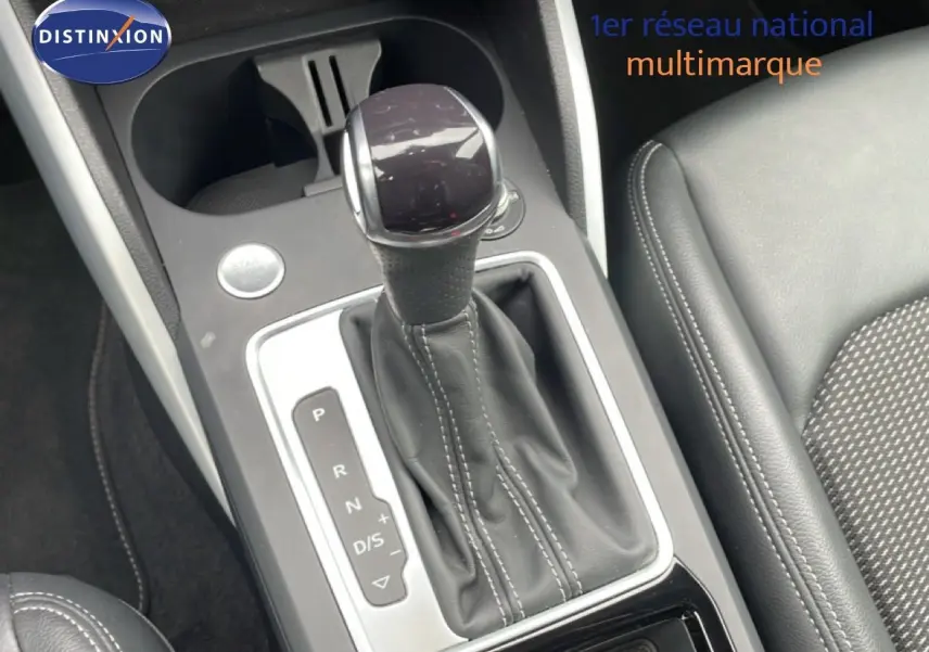 Gros plan sur la console centrale de l’Audi Q2 noire, mettant en valeur le levier de vitesses automatique et les sièges en cuir.