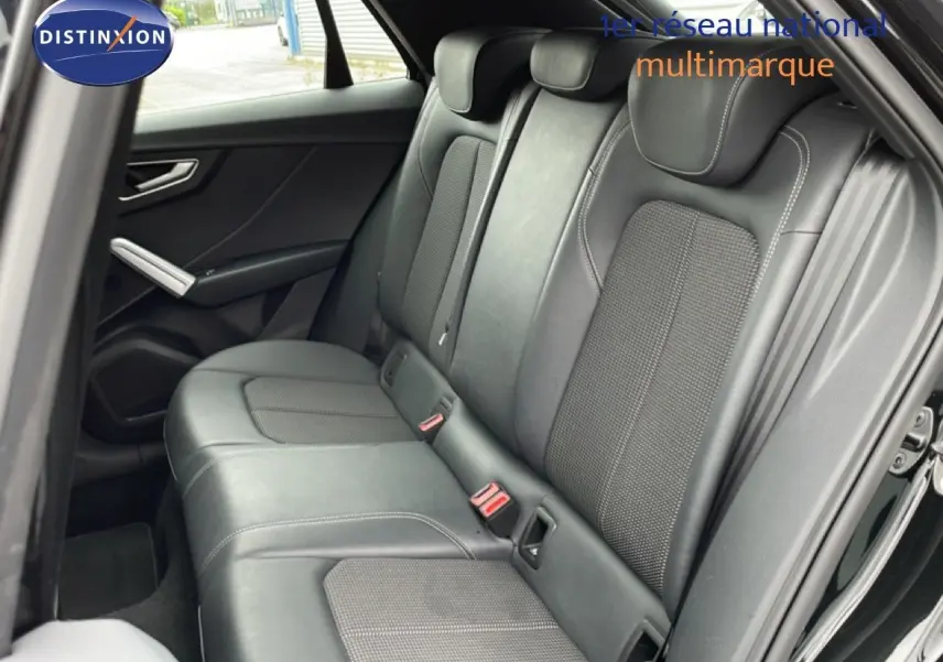 Vue côté gauche des sièges arrière en cuir noir de l'Audi Q2 2025 finition S-Line, avec ceintures rouges visibles.