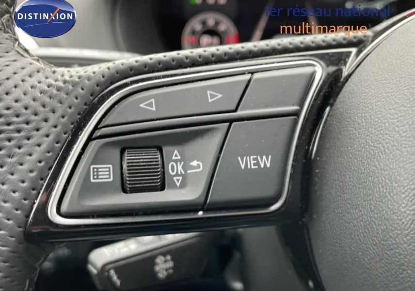 Gros plan sur les commandes multifonctions noires du volant perforé d’un Audi Q2 35 2.0 TDI S-Line 2025.