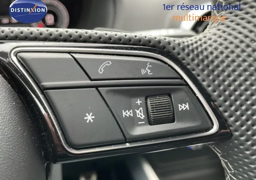 Gros plan sur les commandes audio et téléphone au volant en cuir perforé noir de l'Audi Q2 noir mito metal.