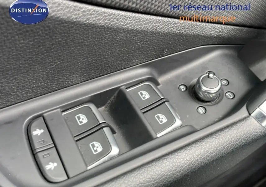Gros plan sur les commandes de lève-vitres et réglage des rétroviseurs côté conducteur d'un Audi Q2 noir mito metal.