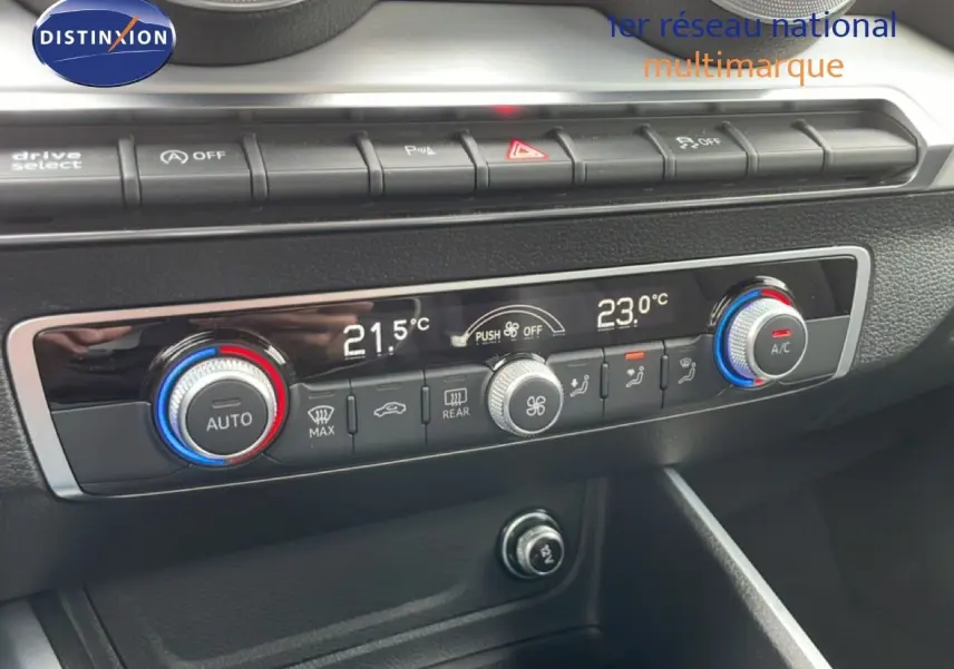 Gros plan sur la console centrale de l'Audi Q2 2025 noire, montrant les commandes de climatisation digitale et boutons de fonction.