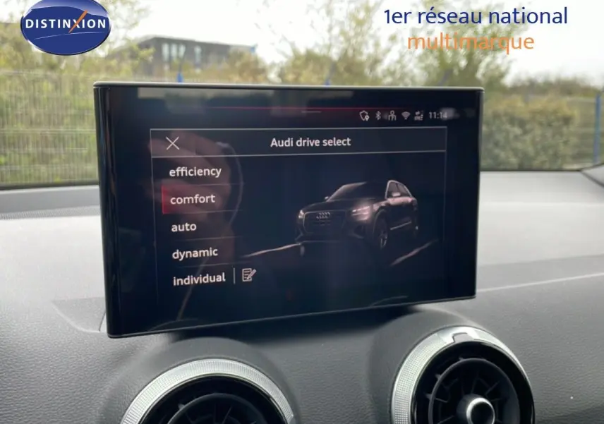Écran central affichant le menu Audi drive select avec une image du SUV Audi Q2 noir mito metal en vue 3/4 avant.