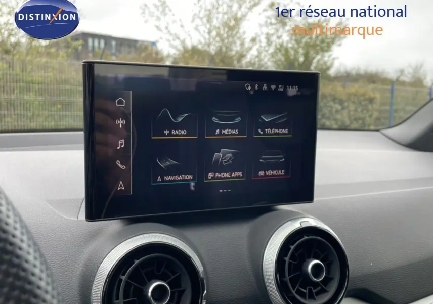 Écran tactile central de l’Audi Q2 noir mito métal, vue intérieure sur la console avec aérateurs ronds argentés.