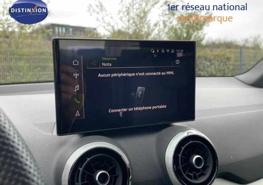 Écran central tactile et aérateurs ronds du tableau de bord d’un Audi Q2 noir mito metal, vue intérieure avant.