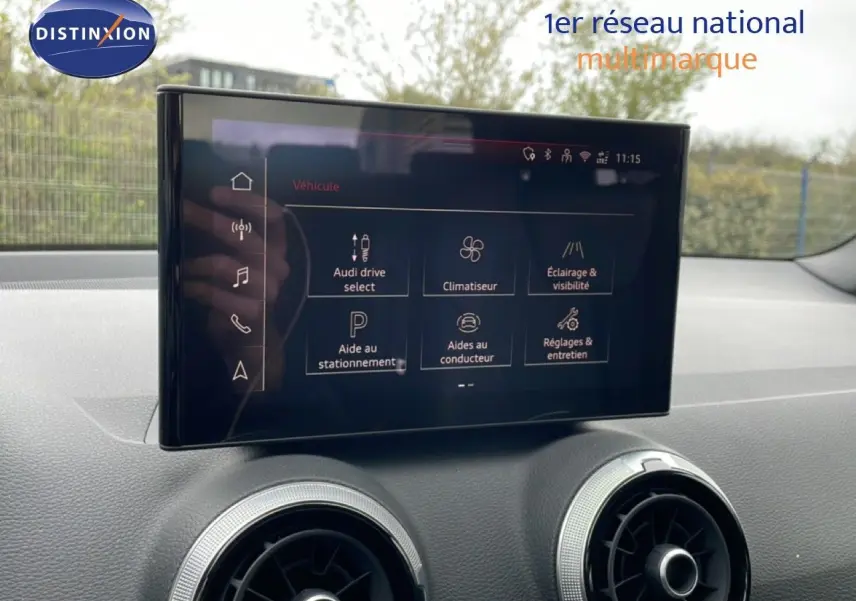 Écran tactile central affichant les options du véhicule dans l'habitacle d'un Audi Q2 noir, vue de face.