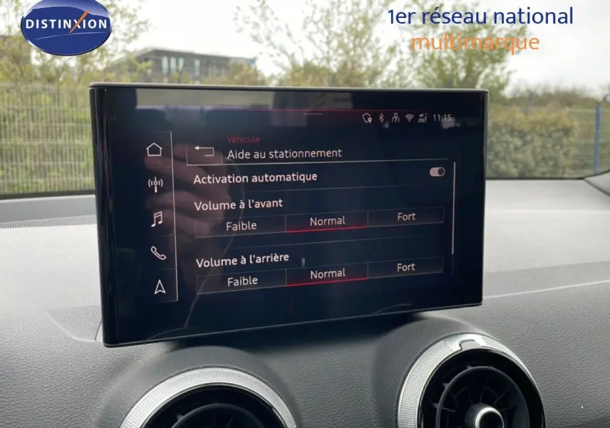 Écran tactile central de l'Audi Q2 noir mito metal, affichant les réglages d'aide au stationnement et volume audio.