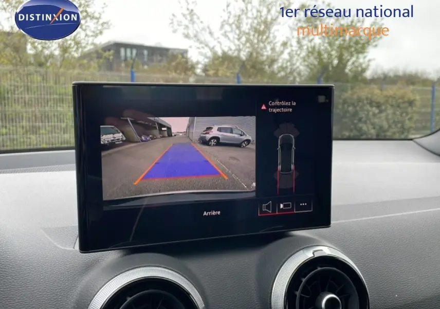Vue intérieure sur l'écran multimédia affichant la caméra de recul de l'Audi Q2 noir mito metal, avec tableau de bord et aérateurs visibles.