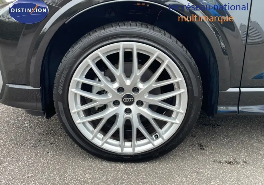 Gros plan sur la roue avant gauche d’un Audi Q2 noir mito metal avec jante alliage argentée multi-branches.