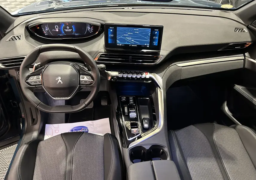 Vue intérieure avant du Peugeot 5008 2024 avec tableau de bord numérique et écran central tactile, sièges noirs et détails argentés.