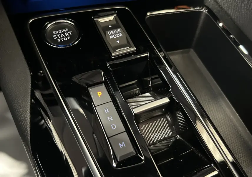 Gros plan sur la console centrale noire brillante du Peugeot 5008 II Ph.2 avec boutons Start/Stop et Drive Mode.