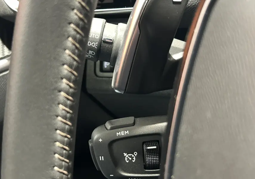 Gros plan sur la commande de régulateur de vitesse au volant en cuir du Peugeot 5008 Bleu Célèbes 2024.
