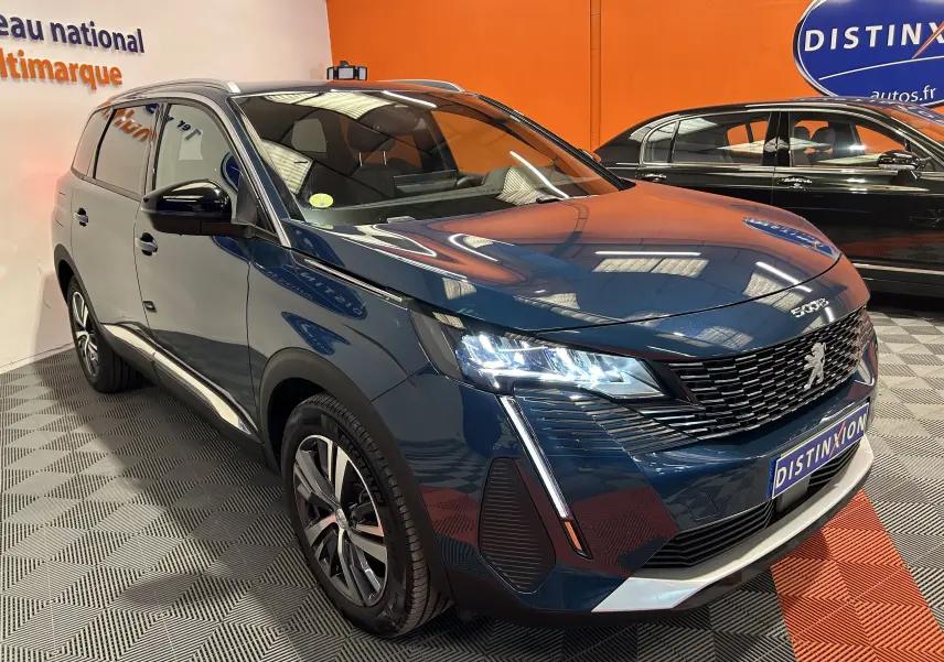 Peugeot 5008 Bleu Célèbes en 3/4 avant droit, phares LED allumés et calandre distinctive dans un showroom.
